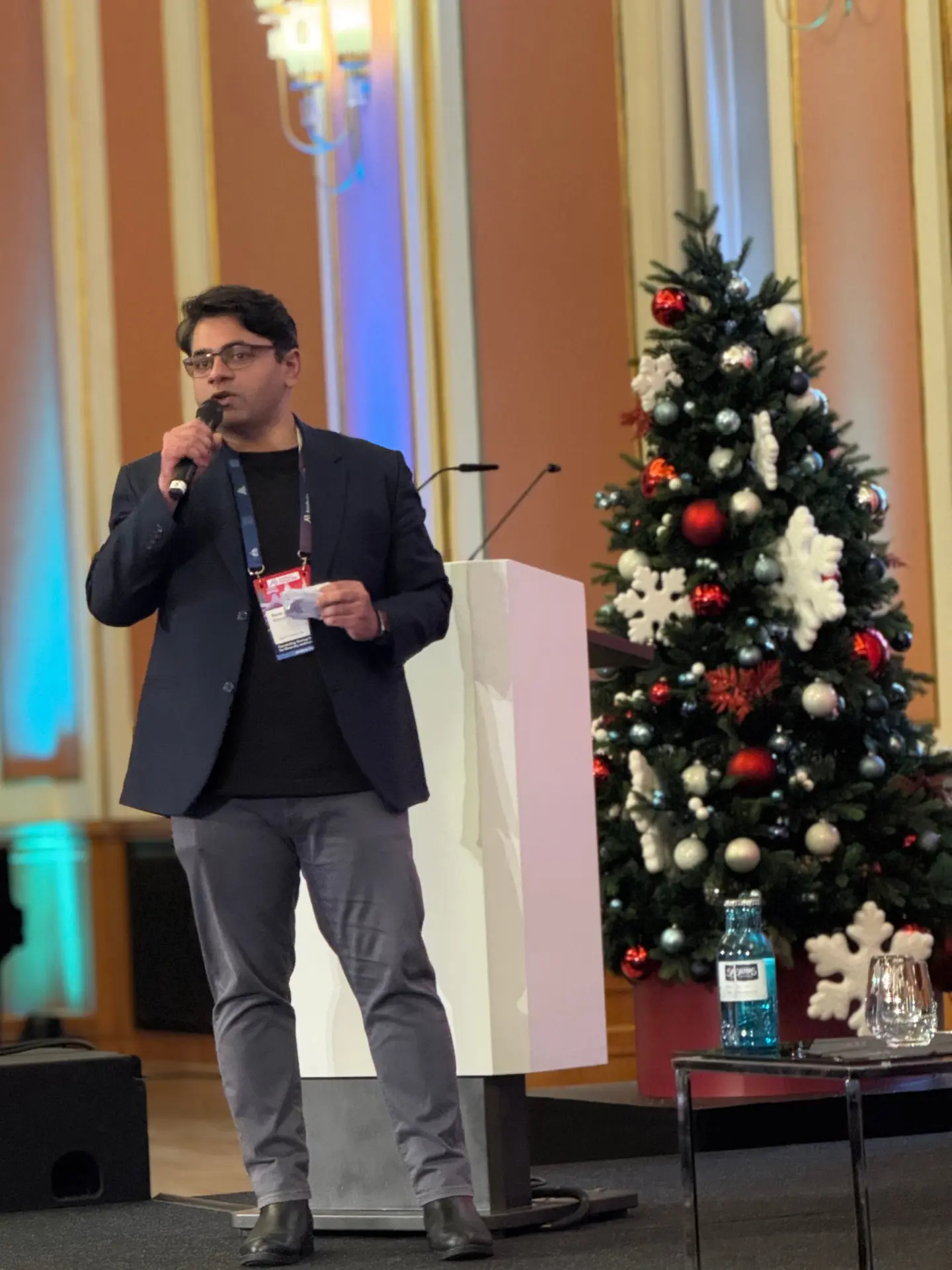 Haris Rehman hosting a panel on stage in Berlin, holding a microphone